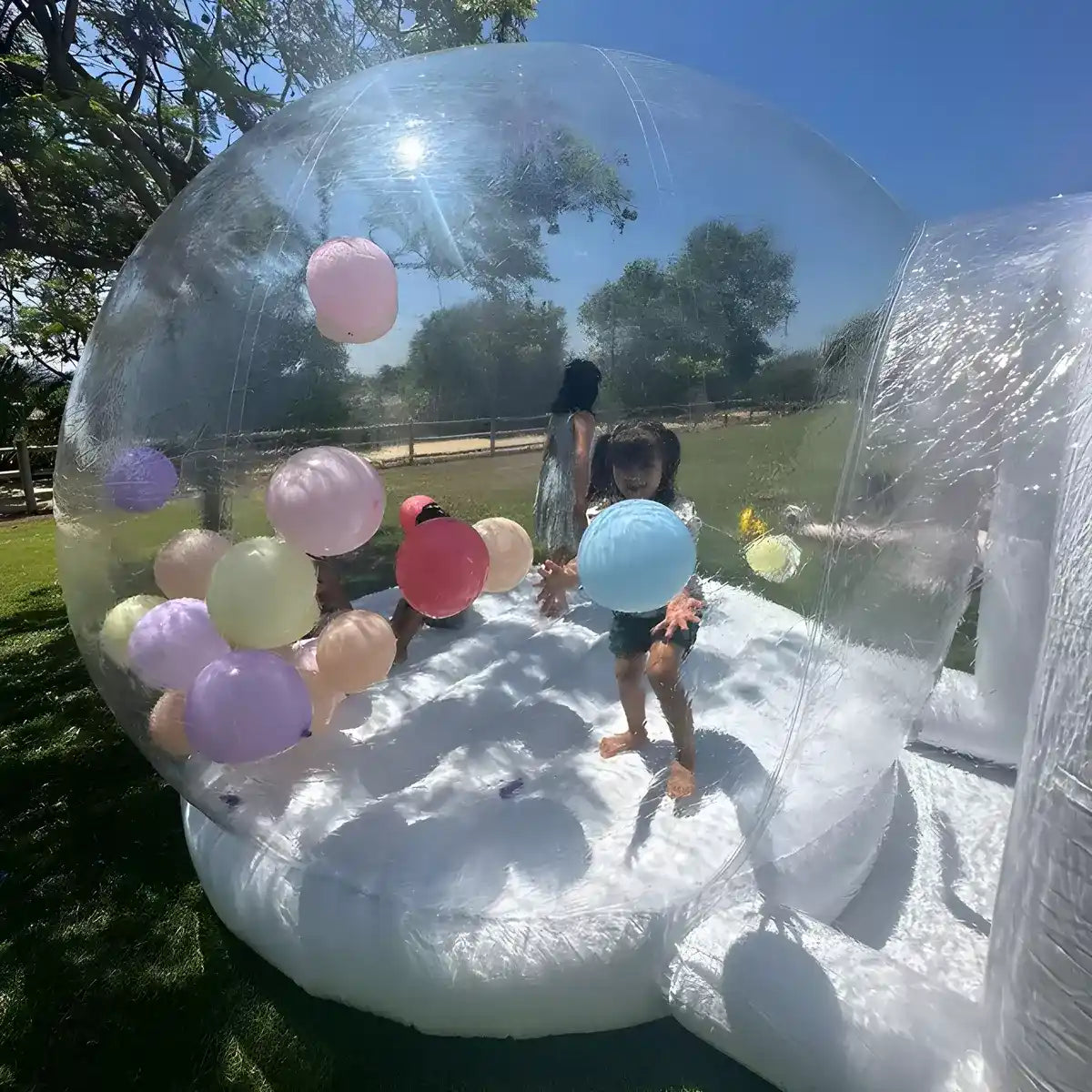 A close up shot into the bubble bounce house with kids playing with balloons