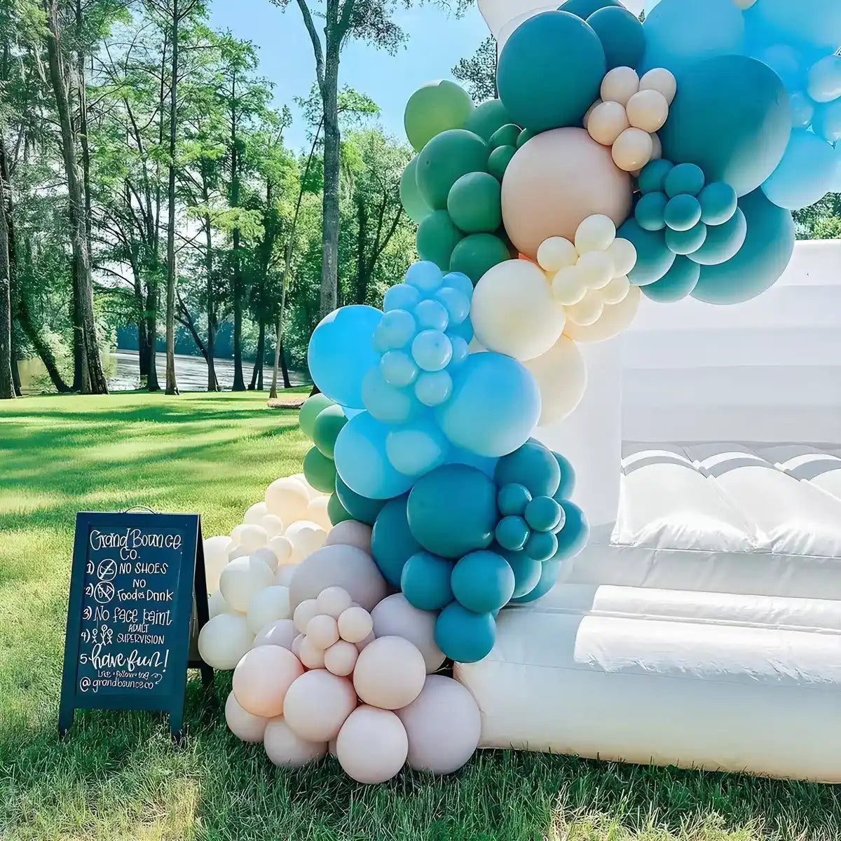 White bounce house decorated with balloons and birthday party signpost